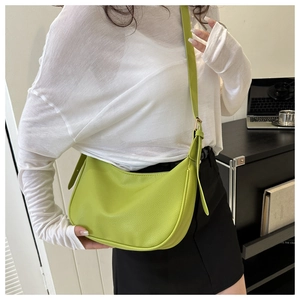 Detail view of avocado green lychee texture leather crescent shoulder bag on model