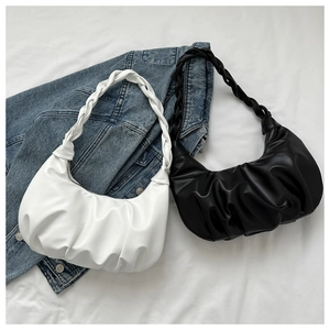 Detail of minimalist pleated dumpling bags in black and white with woven shoulder straps