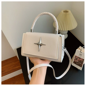 Close-up of white lychee leather handbag featuring a silver star-shaped metal clasp