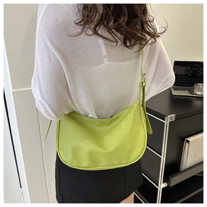 Detailed back view of lime green pebbled leather crescent shoulder bag worn by a model