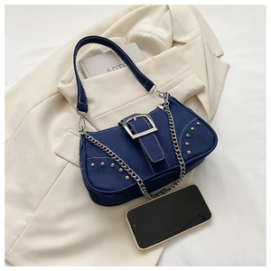 Detailed view of dark blue denim shoulder bag with metal buckle and studs decoration