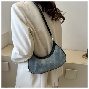 Detail of crescent denim shoulder bag with leather piping and gold lettering