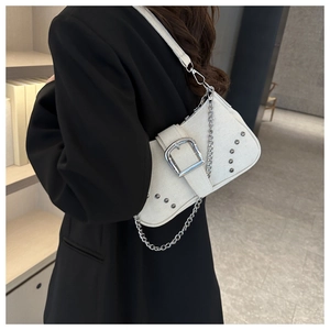 Detail of white baguette bag with large silver buckle and rivet accents on black blazer
