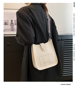 Creamy white lychee leather crossbody bag with striped webbing strap on model