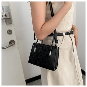 Detail of black faux crocodile skin texture and silver hardware on a chic tote bag