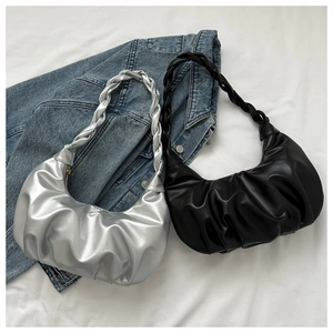 Detail of ruched cloud bags in silver and black with woven handles on denim background