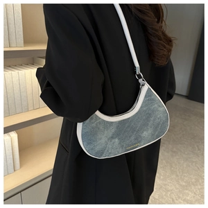 Detail of denim crescent underarm bag with white leather trim and fashion lettering