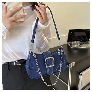 Detail of dark blue denim shoulder bag featuring white contrast stitching and silver chain