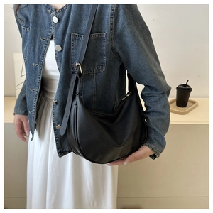 Detail of black pebbled leather half-moon bag with adjustable strap on a model