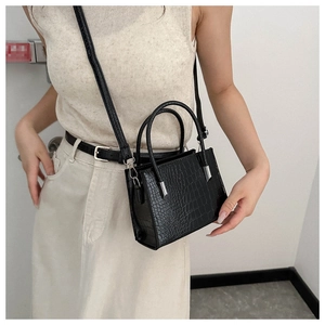 Close-up of black crocodile pattern faux leather texture with silver metal hardware detail