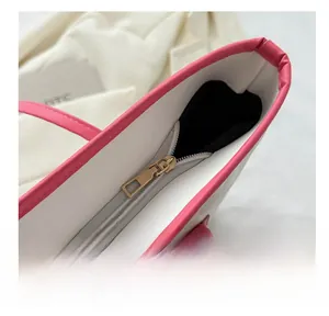 Gros plan sur la fermeture éclair dorée et le bord contrasté rose du sac cabas blanc