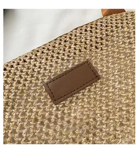 Vue détaillée de la texture en paille tressée et de l'écusson en cuir sur le sac