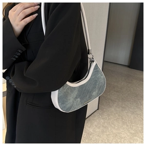 Detail of blue denim crescent bag with white leather trim and gold fashion lettering