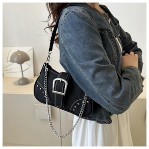Detail of a chic black underarm bag featuring large silver buckles and a chunky metal chain