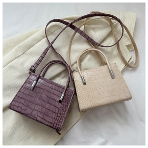 Detailed view of crocodile pattern faux leather tote bags in purple and cream beige colors