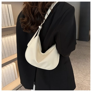 Close-up of minimalist cream half-moon underarm bag with lychee texture on model