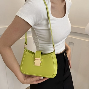 Sac sous le bras vert herbe en cuir avec boucle dorée porté par un mannequin au style épuré