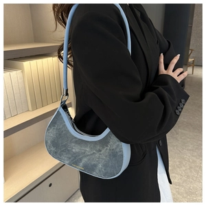 Detail of blue denim hobo bag featuring contrast leather trim and golden logo print