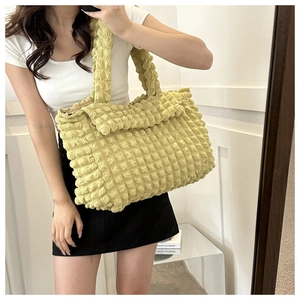 Macro detail of lemon yellow puffy tote bag featuring pleated cloud bubble texture and soft handle