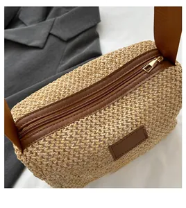 Vue détaillée du sac en paille tressée avec bordure en cuir marron et sangle