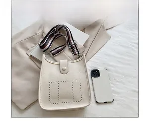 Detail of cream bucket bag with lychee texture and striped woven shoulder strap