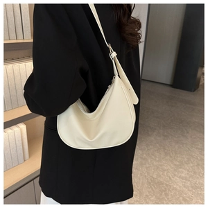 Close-up of creamy white hobo bag with pebble leather texture worn by a model in a suit