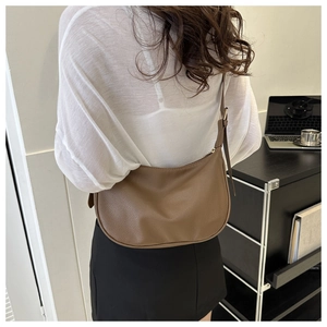 Close-up of a brown litchi pattern leather hobo bag with adjustable strap in daily use