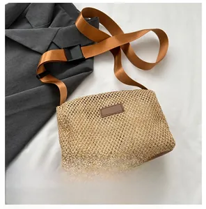 Détail du sac bandoulière en paille tressée avec bandoulière large et texture naturelle