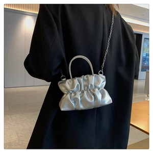 Close-up of a silver pleated cloud bag featuring rhinestone circular handles and chain strap