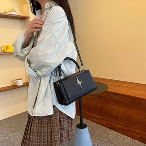 Minimalist black lychee leather crossbody bag with silver star ornament and woven handle