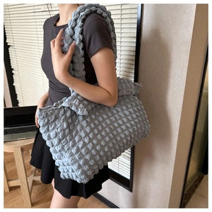 Detail of light blue bubble textured shoulder bag worn by model in casual setting