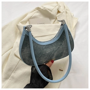 Detail of light blue denim crescent shoulder bag with silver zipper and metal ring connectors