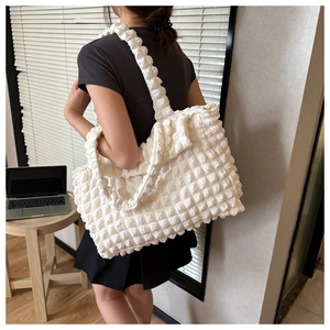 Detailed view of a white bubble textured tote bag worn over the shoulder in a cozy home setting