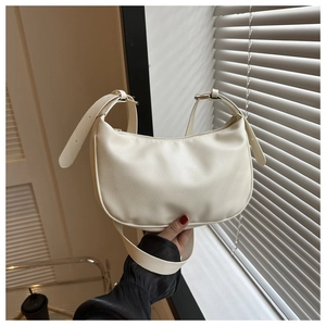 Close-up of litchi textured off-white half-moon shoulder bag with golden buckle