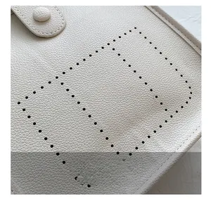 Detail showing pebbled leather texture and perforated pattern on beige bucket bag