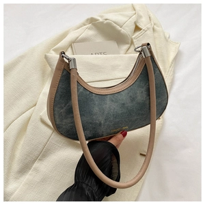 Detail of crescent denim bag with beige leather trim and silver metal hardware accents