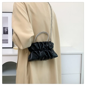 Detail of black pleated cloud bag with rhinestone handle and silver metal chain strap