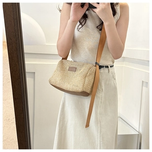 Détail du sac bandoulière en paille tressée avec base marron et sangle en toile sur modèle