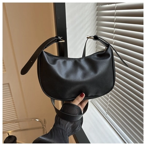 Detail of black pebbled leather crescent bag with adjustable strap and gold buckle