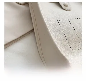 Macro shot showing refined stitching and lychee pattern leather detail on white bucket bag