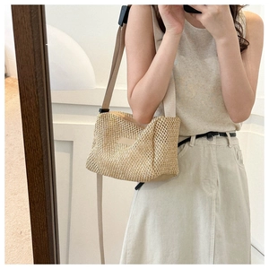 Gros plan détaillé d'un sac bandoulière en paille beige avec sangle réglable en tissu