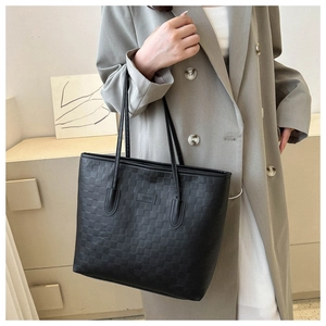 Gros plan d'un grand sac cabas noir à texture tissée avec une étiquette en cuir