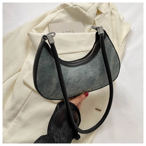Detail of denim crescent bag with black leather trim and silver metal hardware accents