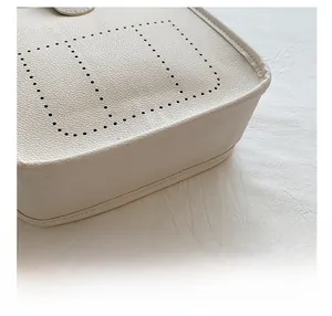 Detail view of white pebbled leather texture with perforated H pattern on bucket bag