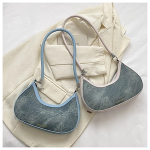 Detail of light blue and cream crescent hobo bags with denim texture and gold lettering