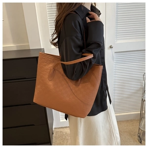Détail d'un sac cabas marron à damier montrant la texture tissée et les fines bandoulières