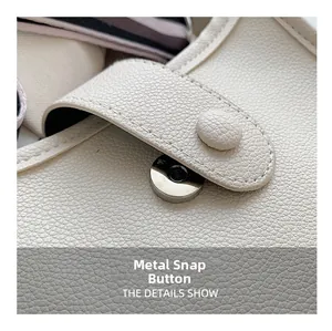 Detail of silver magnetic snap button on off-white lychee grain leather bucket bag