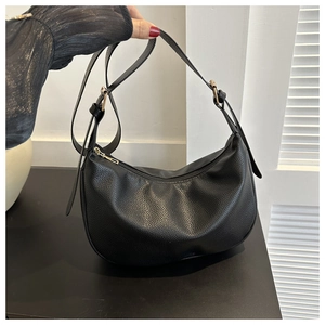 Detail of black lychee grain leather crossbody bag with adjustable strap and gold hardware