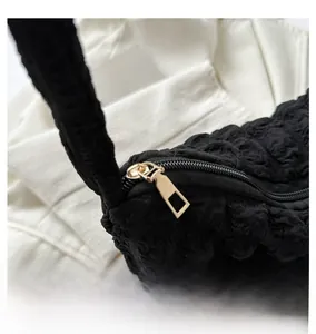 Gros plan sur la fermeture éclair en métal doré et le tissu noir texturé du sac à main