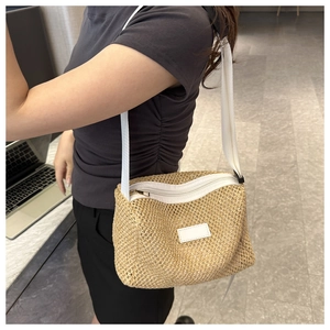 Gros plan détaillé sur la texture en paille tressée et la bandoulière blanche du sac beige